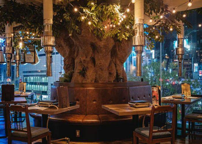 The eye-catching interiors of Shibuya Wagyu Yakiniku USHIHACHI Kiwami, featuring at booth that wraps around a tree trunk.